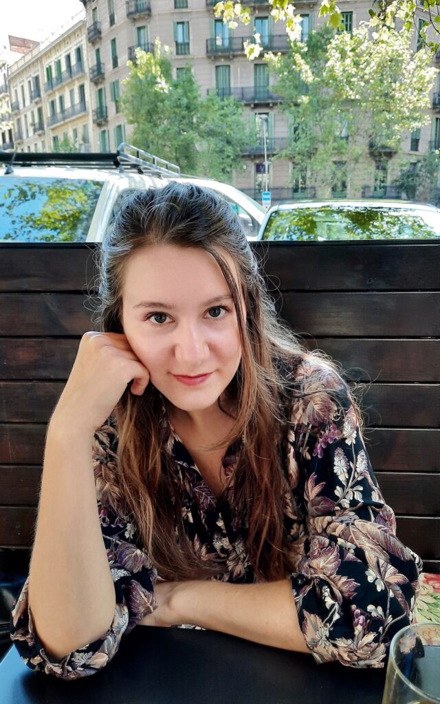 Young entrepreneur of Rêvelance in a café, smiles and thinks about what's next. She loves to rewear Vintage clothes, especially her favourite #1: a gorgeous floral Vintage dress from her granny.